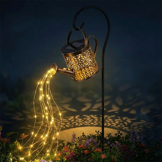 Regadera solar encendida sobre un macizo de flores